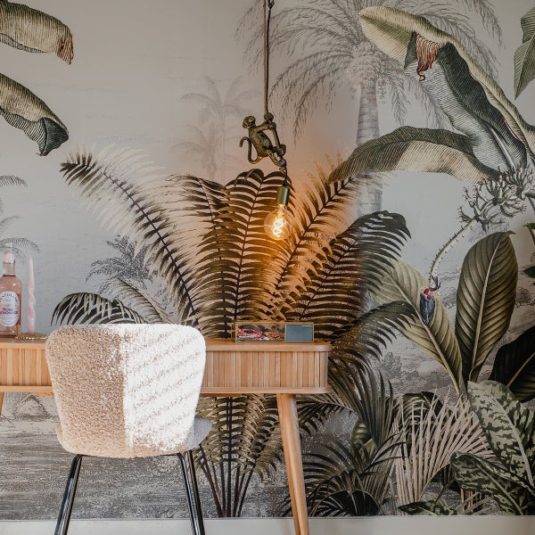 Schreibtisch mit Stuhl und Deko vor einer Dschungeltapete