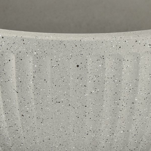 Nahaufnahme der Oberfläche eines grauen Pflanzgefäßes mit schwarz-weißen Sprenkeln und vertikalen Rillen.