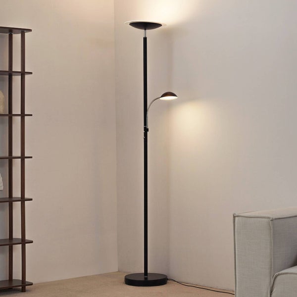 Schwarzer Deckenfluter mit integriertem Leselicht in einem modernen Wohnzimmer neben einem Regal und Sofa.