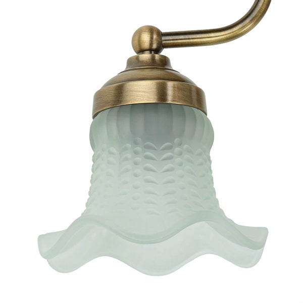 Detailaufnahme einer Wandleuchte mit einem Lampenschirm aus mattiertem Glas und einer Lampenfassung aus Metall