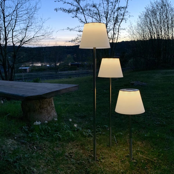 Drei Gartenleuchten mit Lampenschirmen auf einer Rasenfläche