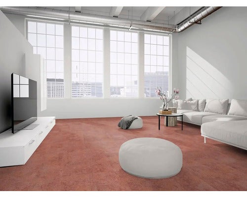 Moderner Loft-Wohnraum mit großformatigen Bodenfliesen in Rostoptik, weißem Sofa und großen Fenstern im Industriedesign.