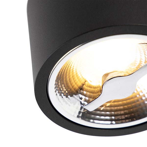 Nahaufnahme eines schwarzen zylindrischen Strahlers mit eingeschalteter Lichtquelle und strukturiertem Reflektor.