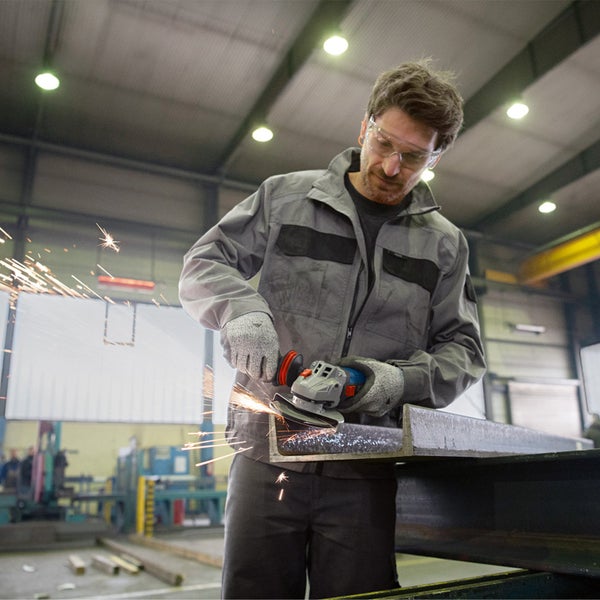 Mann arbeitet mit Winkelschleifer an Metallstück in Werkstatt