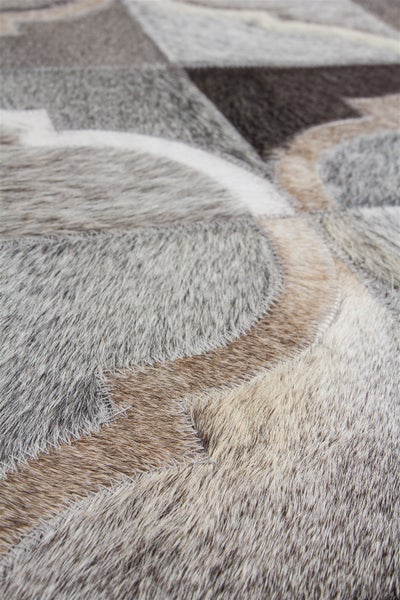 Teppich aus Kuhfell-Patchwork mit geometrischem Muster und sichtbaren Nähten.