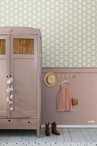 Vliestapete mit weißem Kreismuster auf grünem Grund in einem Kinderzimmer mit rosa Wandpaneelen, Schrank und Kleiderhaken.