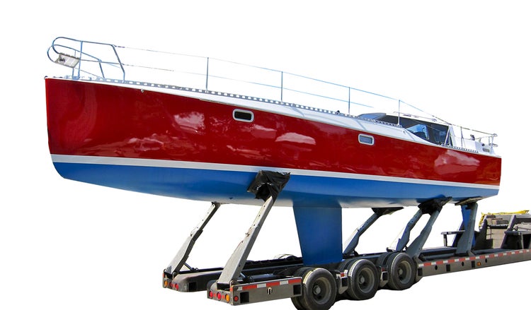 Eine Segelyacht auf einem LKW Auflieger mit Anhängerkupplung für den Transport.