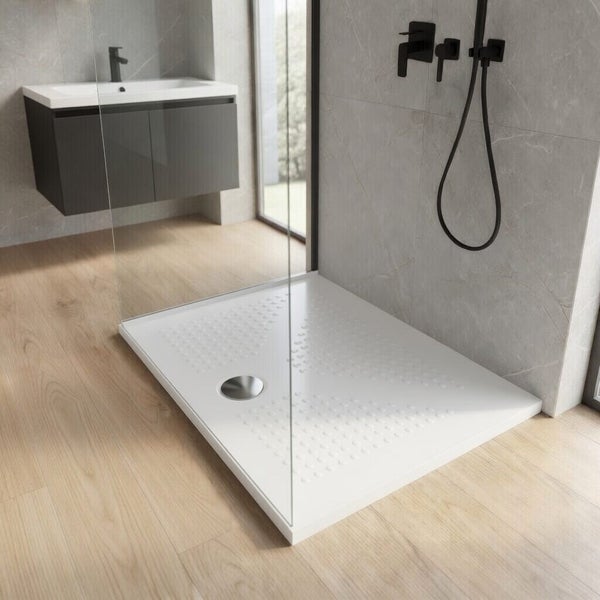 Moderne, rechteckige Duschwanne in einer hellen, begehbaren Dusche mit Glaswand und grauen Wandfliesen im Badezimmer.