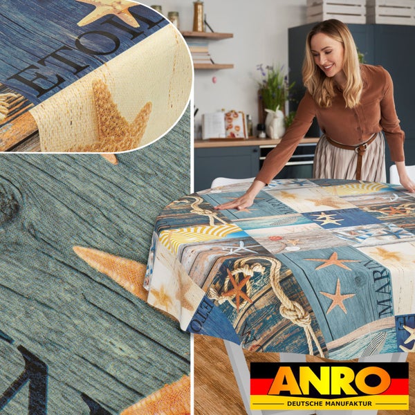 In einer hellen Küche liegt eine runde Wachstuch-Tischdecke mit maritimem Motiv aus Seesternen, Tauen und Holzoptik. ANRO Deutsche Manufaktur Logo.