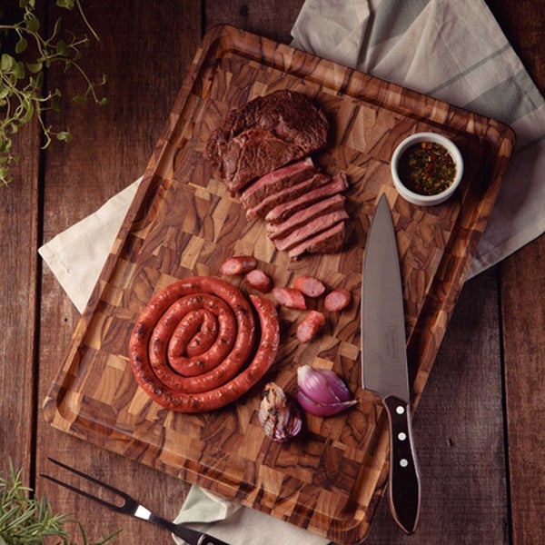 Holzschneidebrett mit Steak, Wurst, Zwiebeln und Messer