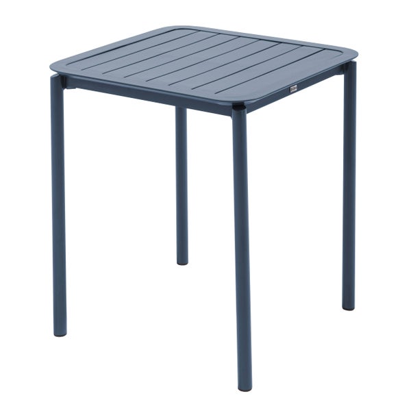 Quadratischer Gartentisch aus blauem Aluminium mit Lattendesign auf einer hellen Holzterrasse mit Wasserflasche und Gläsern.