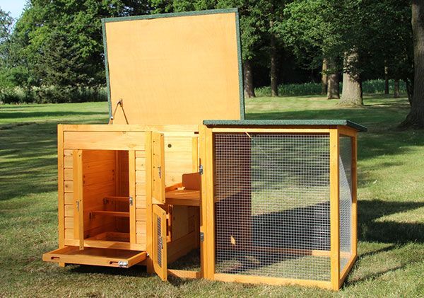 Hühnerstall aus Holz mit integriertem Freilaufgehege, aufklappbarem Dach, mehreren Türen und einer ausziehbaren Wanne auf einer Wiese.