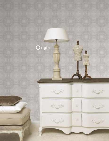 Szene mit einer Kommode, einer Lampe und dekorativen Schneiderpuppen vor einer gemusterten Tapete