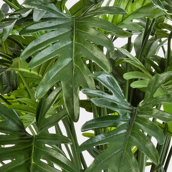 Künstliche Pflanze Philodendron mit großen grünen Blättern im schwarzen Kunststofftopf.