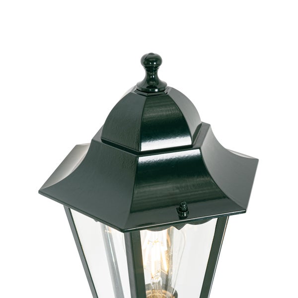 Schwarze Außenleuchte im Laternenstil mit Glaseinsätzen und brennendem Leuchtmittel.