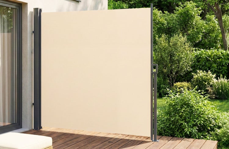 Ausziehbare Seitenmarkise auf einer Holzterrasse als Sichtschutz und Windschutz vor einem grünen Garten.