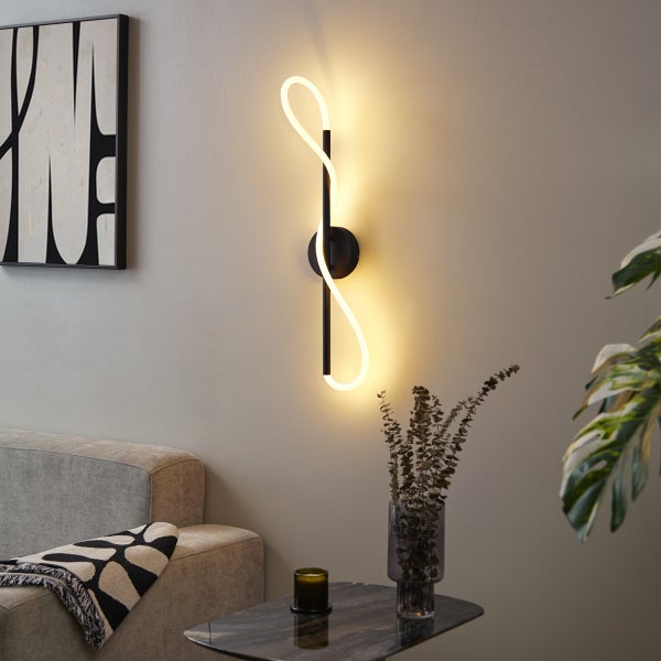 Moderne Wandleuchte mit geschwungenem Design und warmem Licht in einem Wohnzimmer.