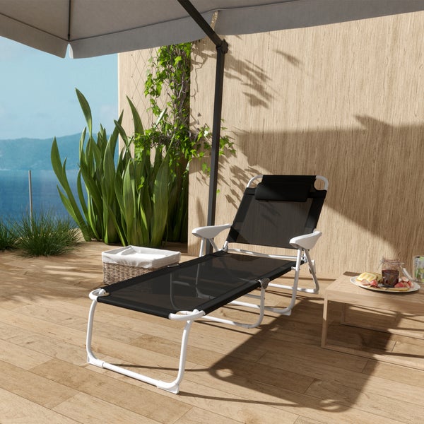 Schwarze Sonnenliege mit weißem Gestell auf einer hellen Holzterrasse mit Sonnenschirm, Beistelltisch und Meerblick.