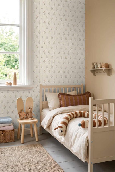 Hell gestaltetes Kinderzimmer mit floral gemusterter Tapete, einem Holzbett und dekorativen Elementen aus Naturmaterialien.