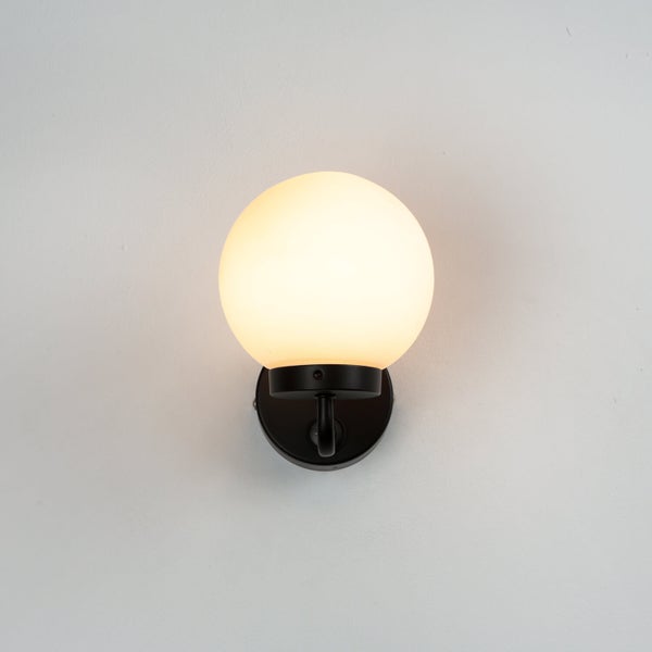Wandleuchte mit runder, leuchtender Glaskugel und dunkler Halterung