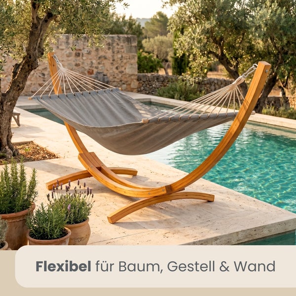 Hängematte mit bogenförmigem Holzgestell auf einer Steinterrasse neben einem Pool.