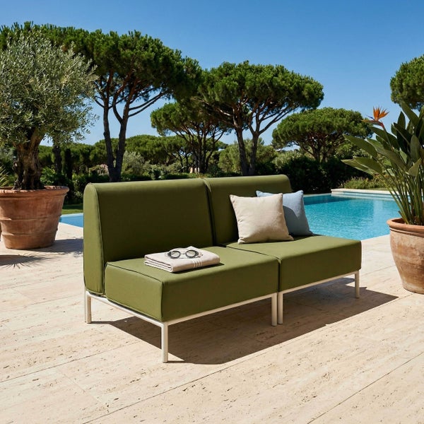 Modernes olivgrünes 2-Sitzer Lounge-Sofa mit weißem Metallgestell auf einer hellen Steinterrasse am Pool mit großen Pflanzenkübeln.