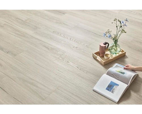 Heller Holzboden mit dekorativen Elementen: Tablett mit Kaffeekanne, Blumenvase und eine Person, die ein Magazin liest