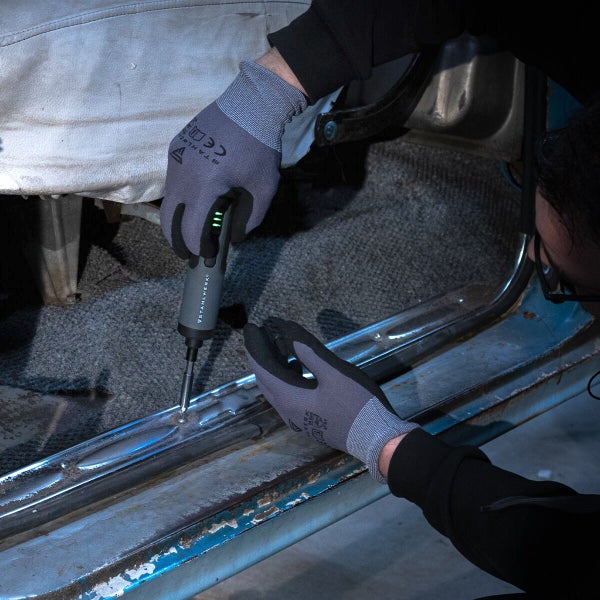 Handwerker befestigt eine Schraube mit einem Akku-Schraubendreher im Auto.