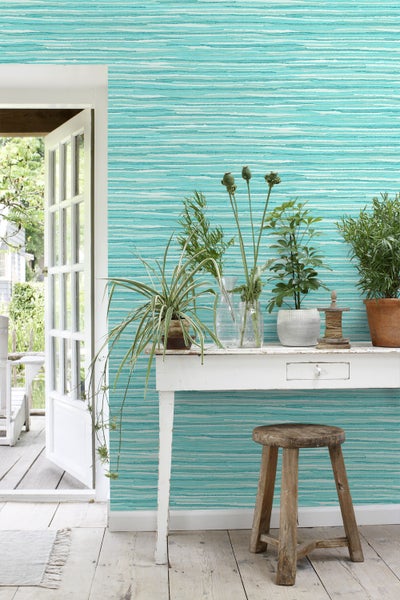 Helles Zimmer mit gemusterter Tapete, dekoriertem Tisch und Holzhocker