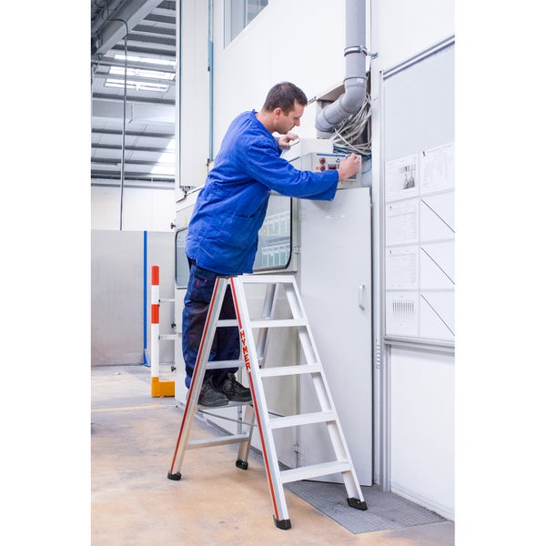 Mann auf einer Trittleiter bei der Arbeit an einer Maschine