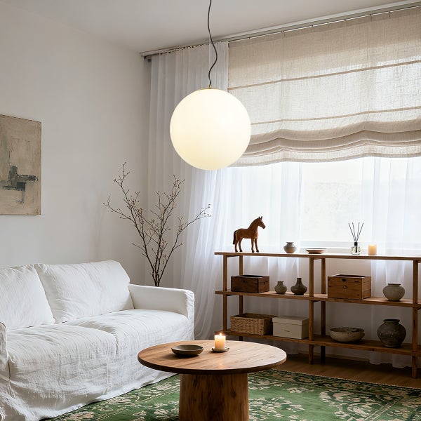 Wohnzimmer mit Sofa, Couchtisch und runder Hängeleuchte.