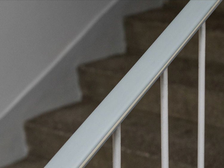 Moderner grauer Handlauf an einer Treppe mit Geländerstäben und Steinstufen.