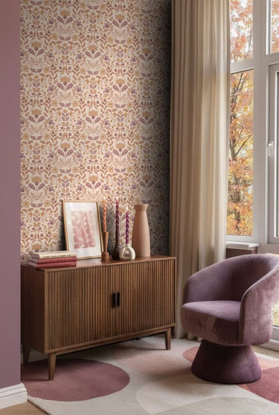 Einrichtungsszene mit einer Kommode, einem Sessel und einer floralen Tapete.