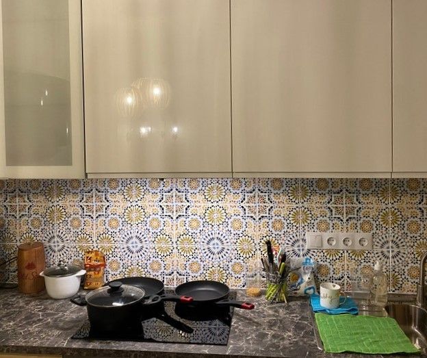 Küchenszene mit Arbeitsplatte, Kochfeld, Töpfen, Pfannen und Fliesenspiegel im Retro-Stil