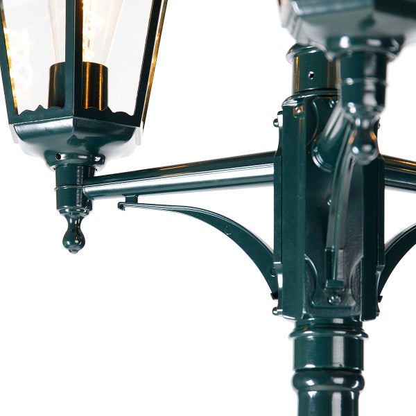 Detailaufnahme eines klassischen Kandelabers für den Außenbereich mit zwei Laternenköpfen und verzierten Halterungen.