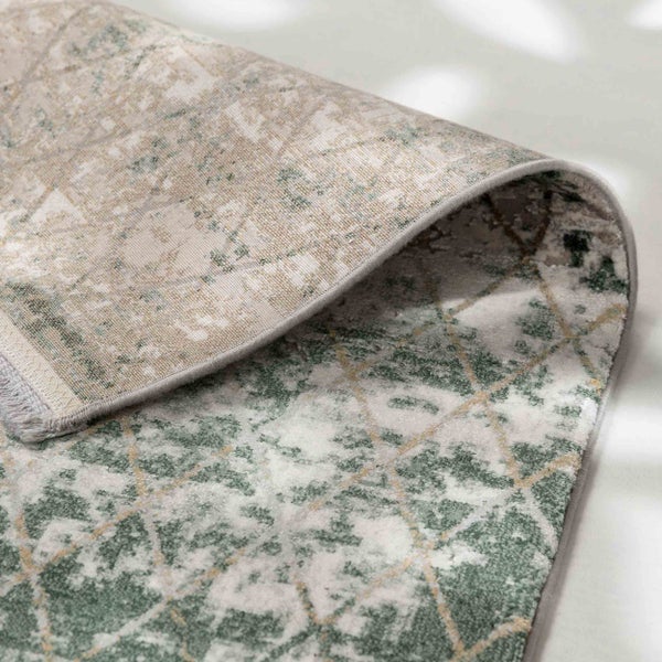 Nahaufnahme eines grün-beigen Teppichs mit geometrischem Vintage-Muster und einer umgeschlagenen Ecke.