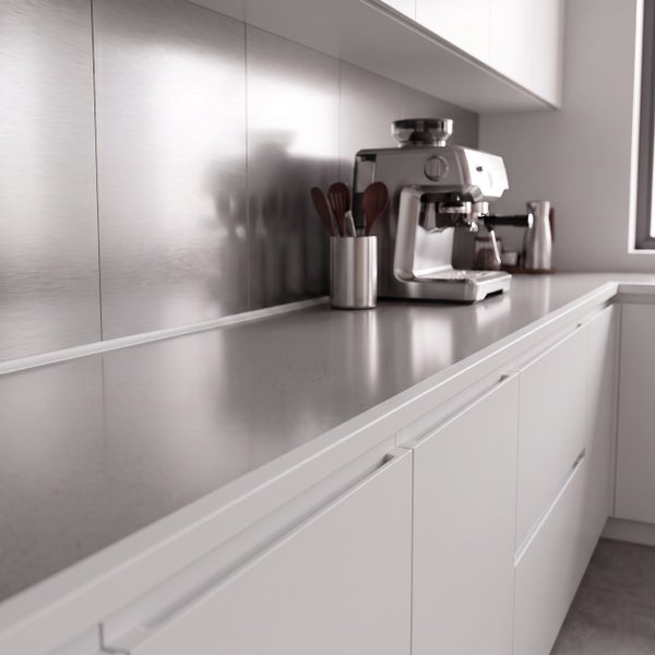 Moderne Küche mit glatter Arbeitsplatte, metallischer Rückwand und Kaffeemaschine auf der Anrichte.