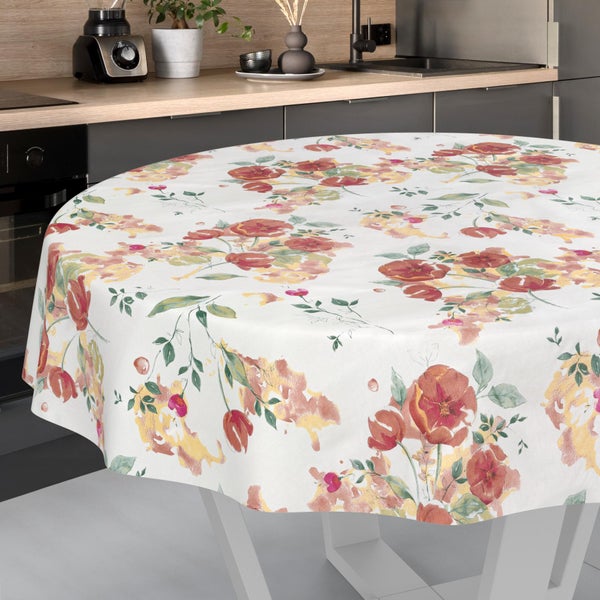 Rundes Tischtuch mit floralem Muster auf einem Tisch in einer hellen, modern eingerichteten Küche mit Holzarbeitsplatte.