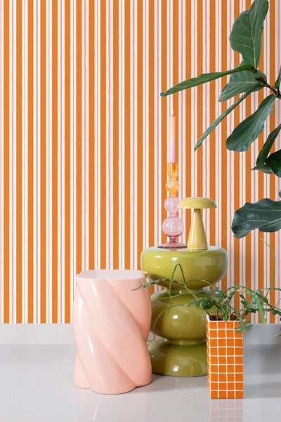 Dekoratives Interieur mit gestreifter Tapete, Beistelltisch und Pflanzen