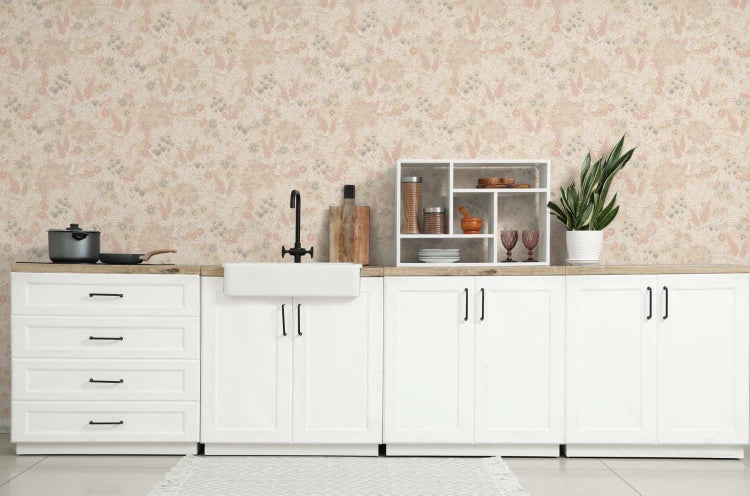 Moderne Küche mit weißen Küchenschränken, Holzarbeitsplatte, Keramikspüle und floraler Tapete in einer hellen und wohnlichen Atmosphäre.