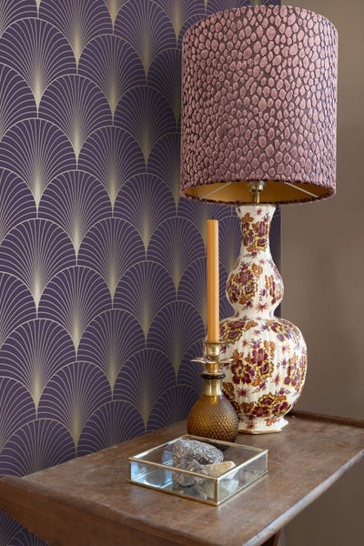 Dekorative Szene mit einer gemusterten Tapete, einer verzierten Lampe und einer Kerze auf einem Tisch.
