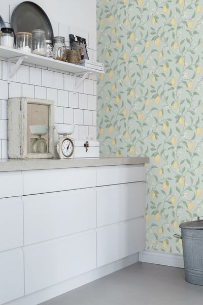 Küchenszene mit Zitrone-Tapete, weißen Schränken und Küchenutensilien auf einem Regal