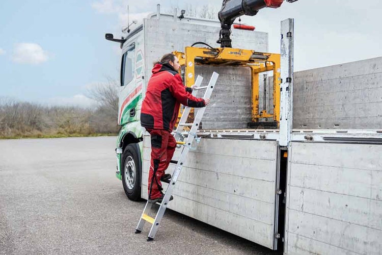 Eine Person steigt auf einer Aluminiumleiter auf einen LKW