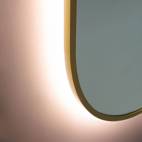 Detailansicht eines Badezimmerspiegels mit abgerundetem goldenem Rahmen und indirekter Hintergrundbeleuchtung.