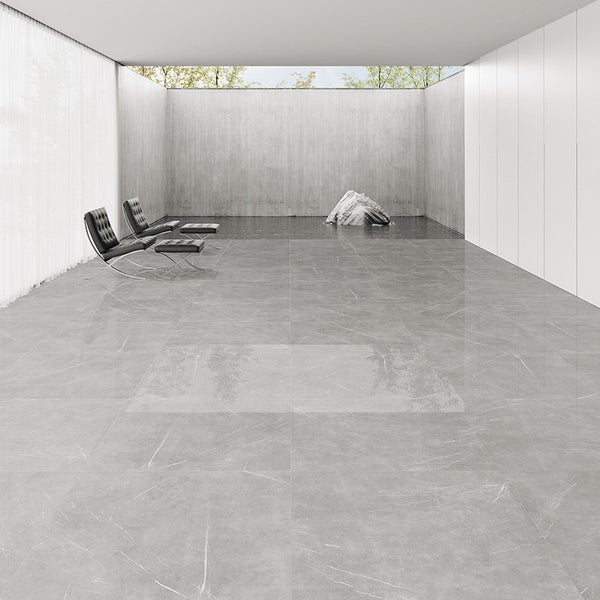 Moderne graue Fliesen in Marmoroptik verlegt in einem großzügigen minimalistischen Raum mit Sesseln und einer Betonwand.
