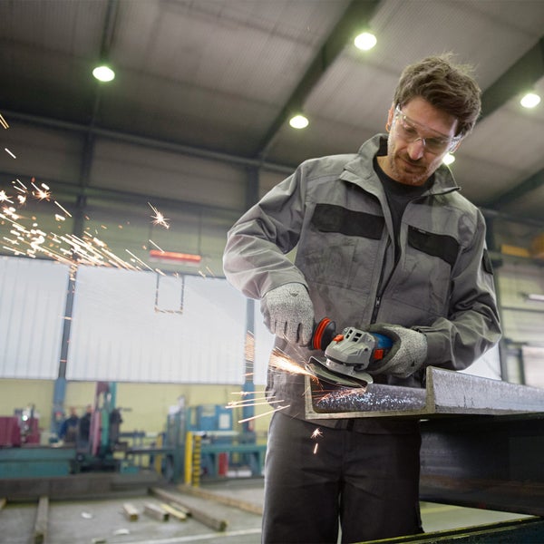 Eine Person schleift mit einem Winkelschleifer ein Metallstück, wobei Funken sprühen.