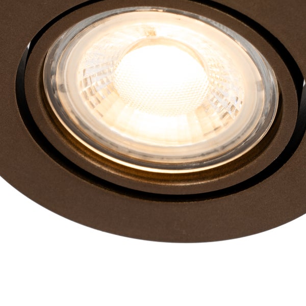 Nahaufnahme eines runden Einbaustrahlers mit bronzefarbenem Metallrahmen und warmweißem LED-Leuchtmittel hinter einer strukturierten Linse.