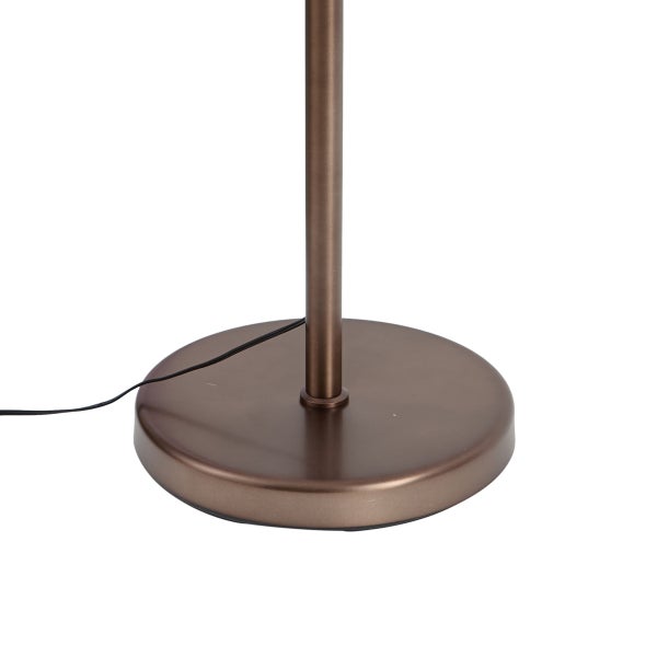 Runder bronzefarbener Metallsockel einer Stehleuchte mit vertikaler Stange und schwarzem Kabel.