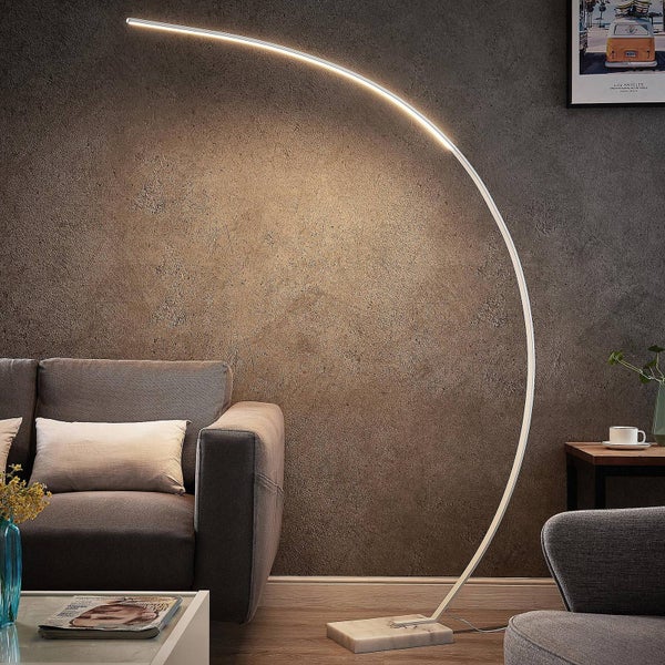 Moderne LED Bogenstehlampe mit schmalem, gebogenem Rahmen und Marmorfuß, beleuchtet ein graues Sofa in einem Wohnzimmer.