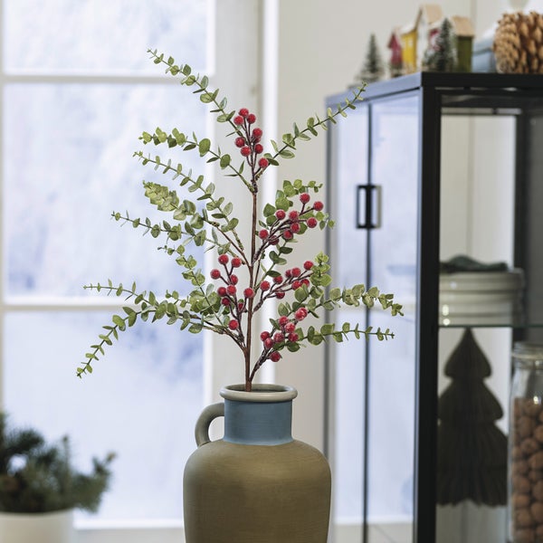 Dekorative Kunstpflanze mit roten Beeren in einer Vase als Zimmerdekoration.